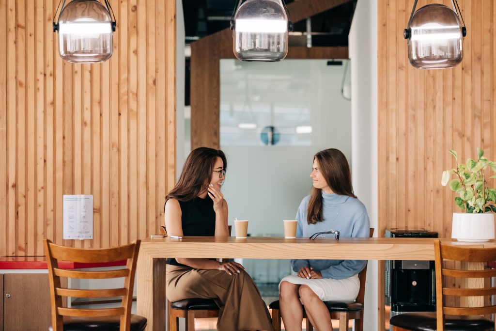 Two friends talking over coffee — building friendships when you feel out of place