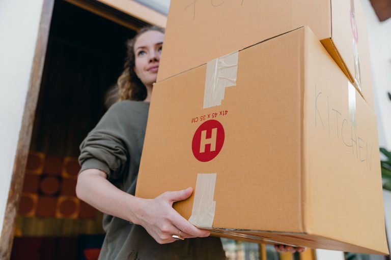 A volunteer carrying moving boxes out of a home — bible verses about helping others in need